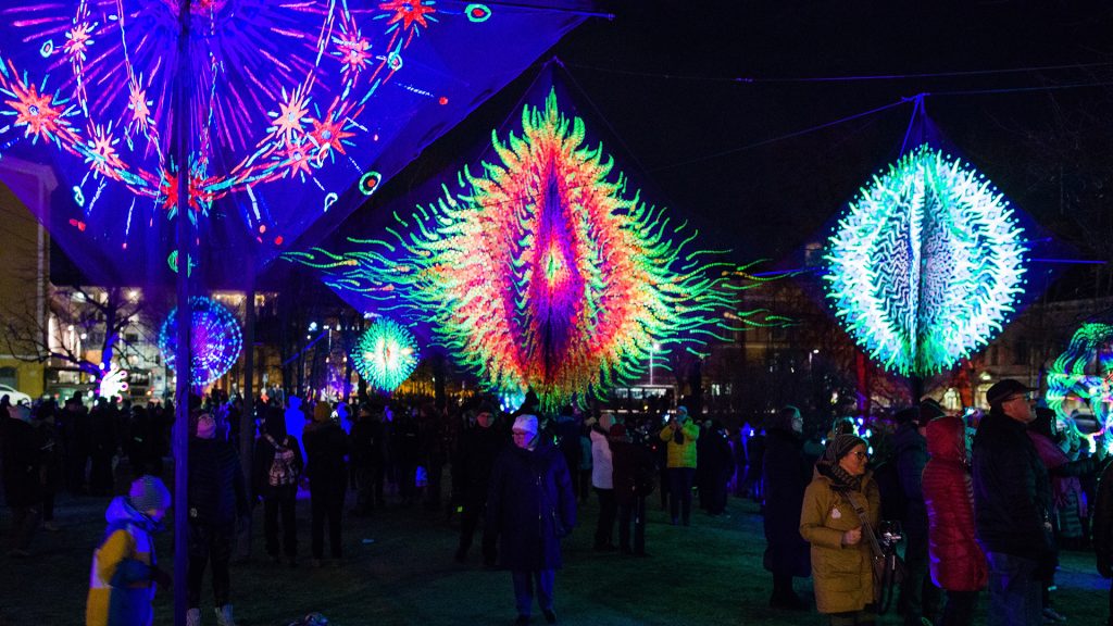 A colorful light work surrounded by people