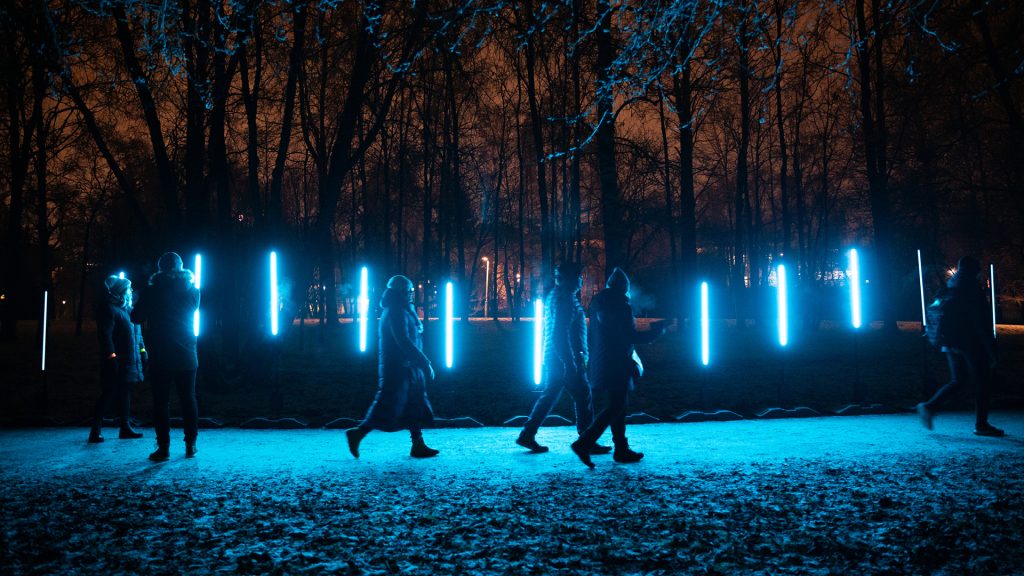 A blue light work with people walking in front of it